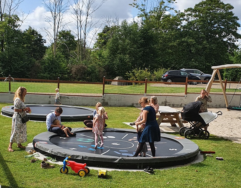 Børn og voksne i fælles leg på trampoliner på overnatningssted ved Billund