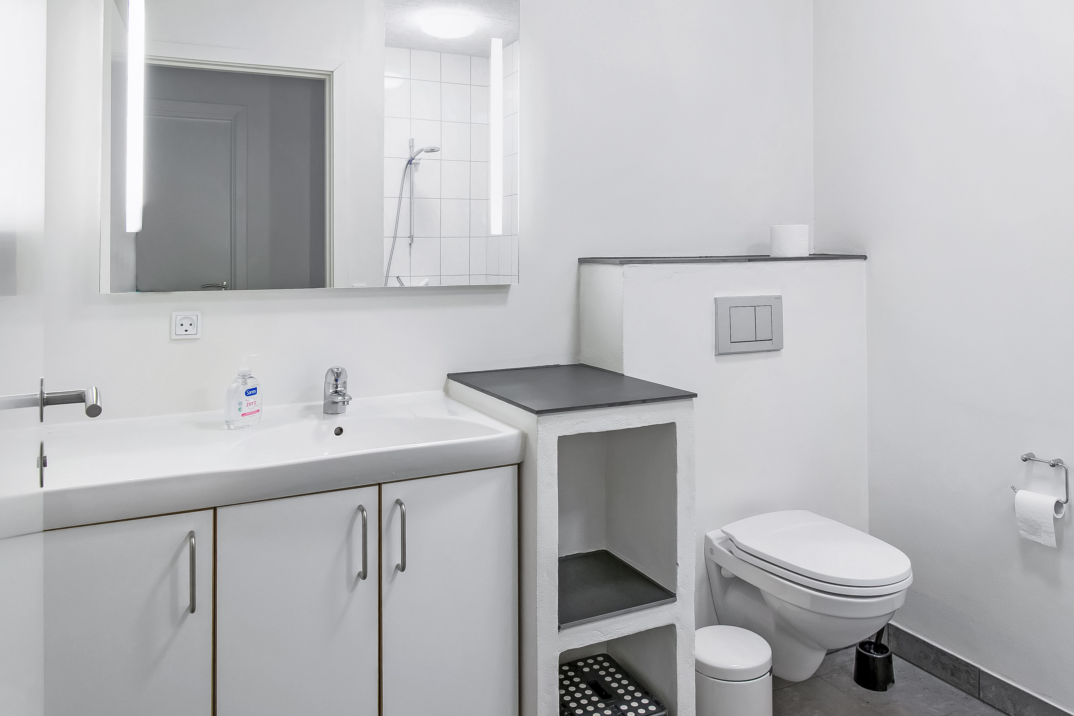 Ferielejlighed - her er badeværelse med skabe, spejl, toilet og bruseniche