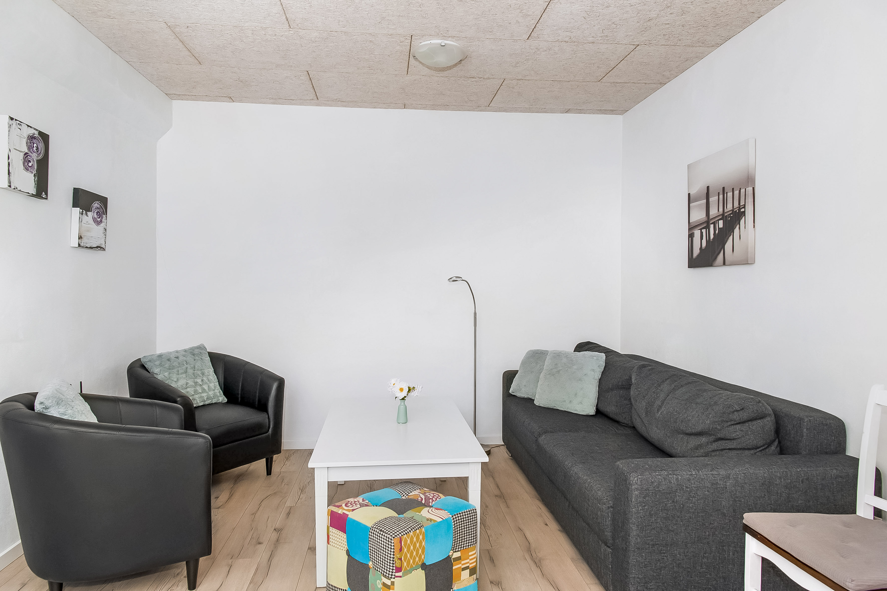 Stor ferielejlighed, her er opholdsstue med magelige møbler, to stole og en dobbelt sovesofa samt sofabord