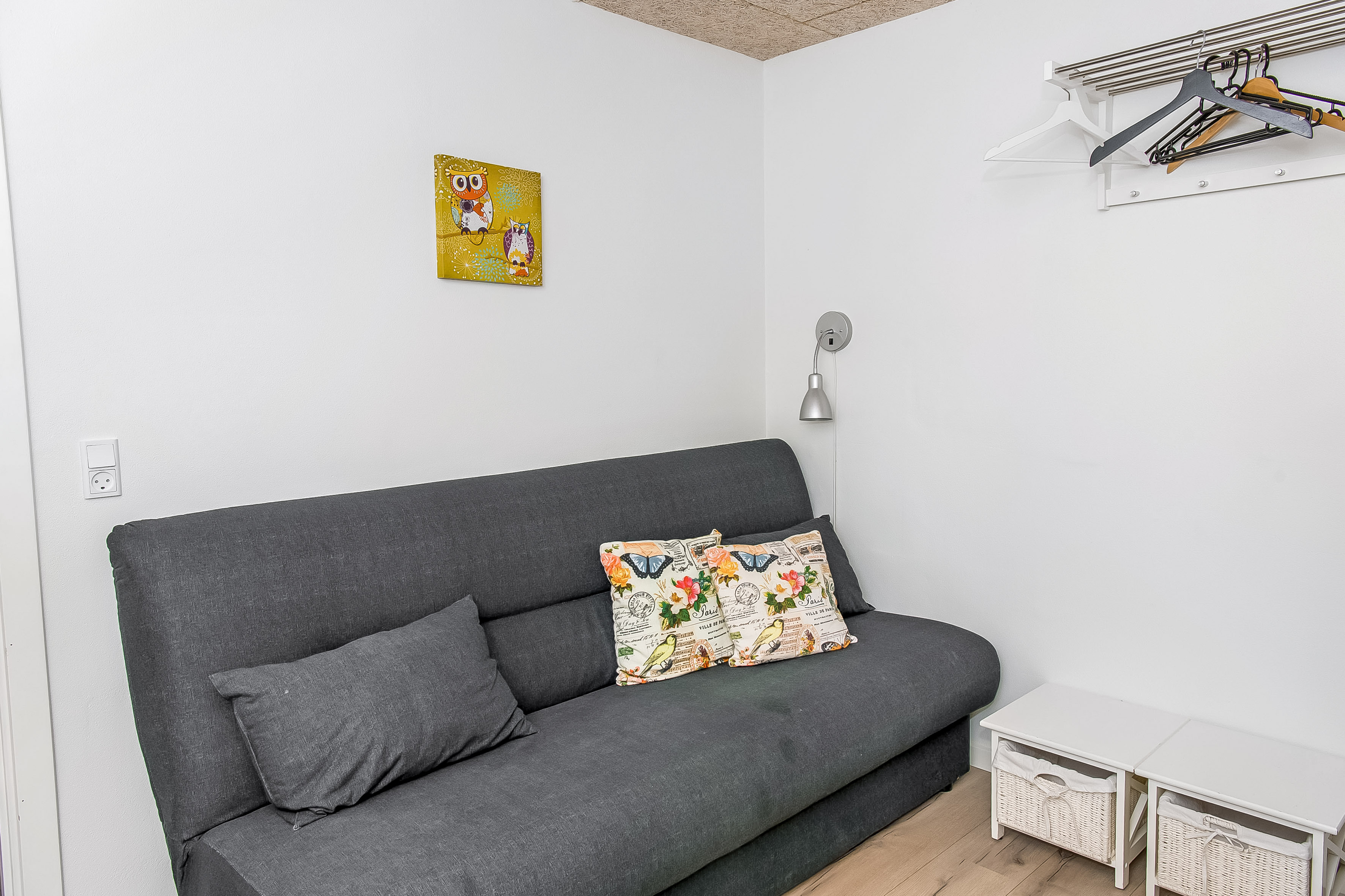 Stor ferielejlighed, her er lille sovesofa med puder, små natborde og hattehylde med bøjler