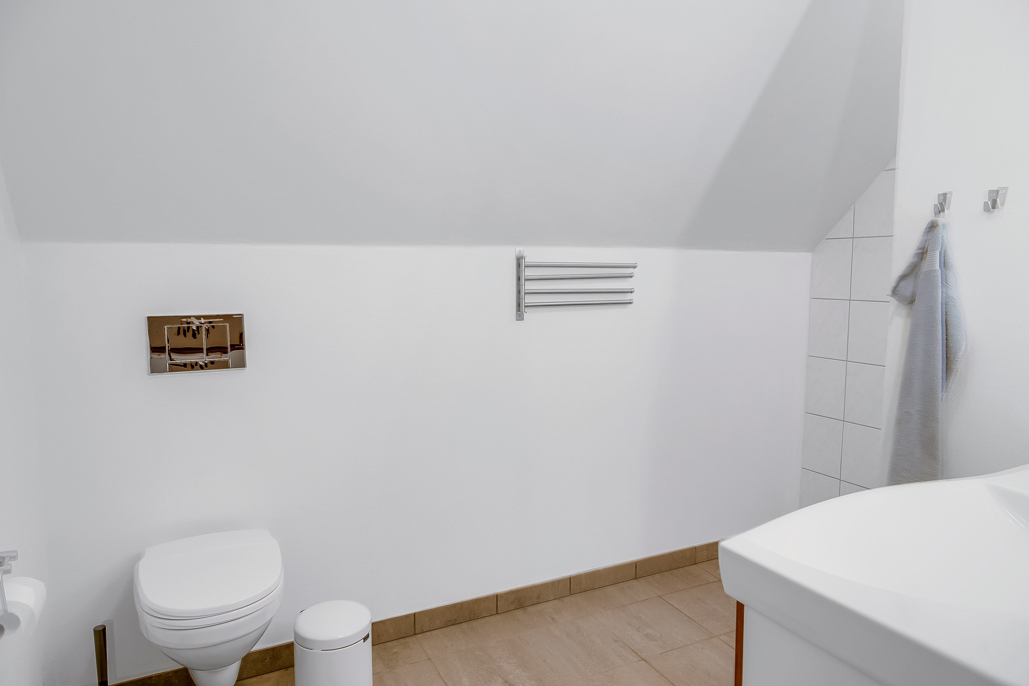 Ferielejlighed, badeværelse med toilet, håndklædestænger, pedalspand og badeværelsesskab 