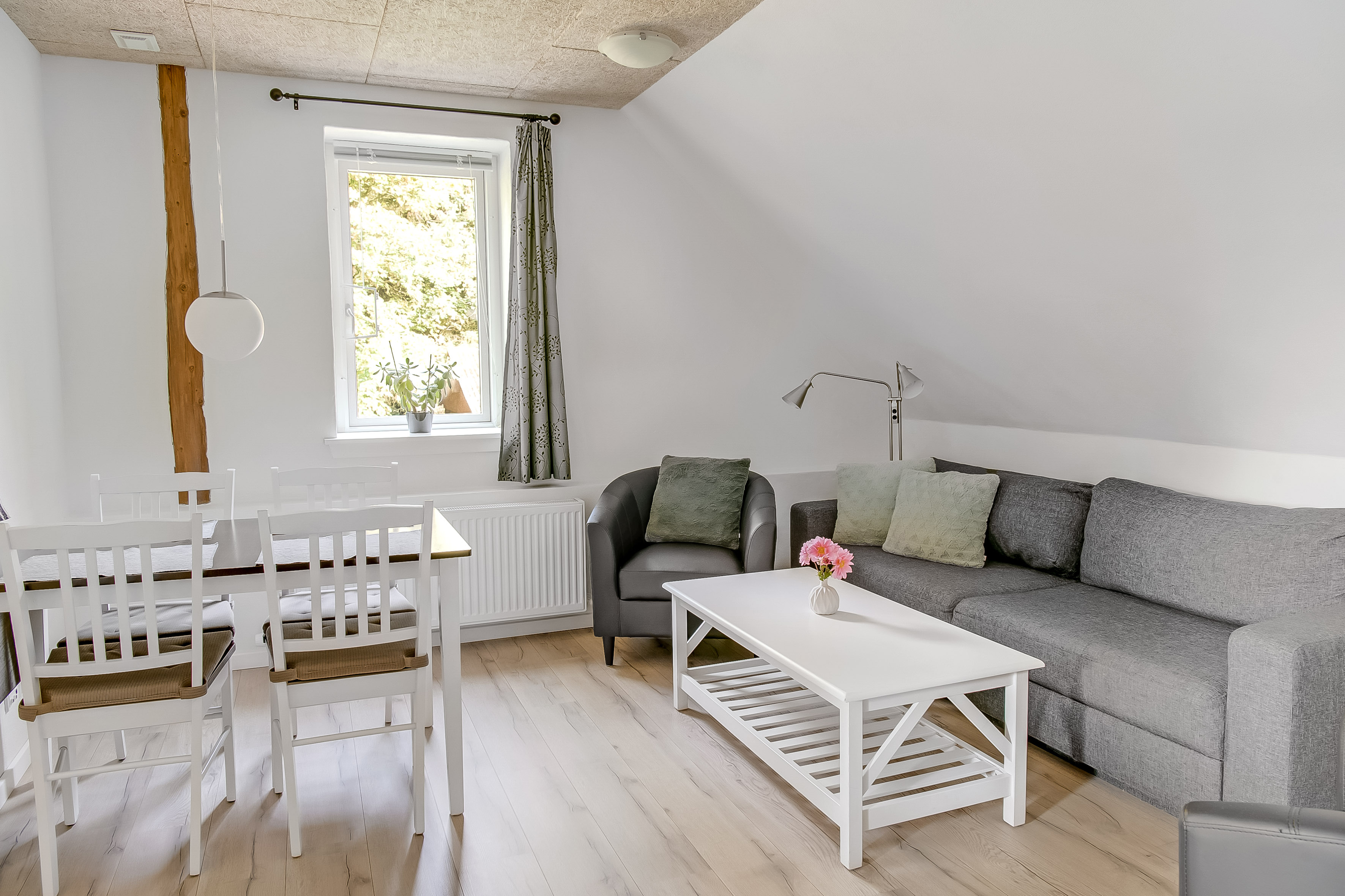 Ferielejlighed, opholdsstue med spiseplads, dobbelt sovesofa, sofabord og udsigt mod øst 