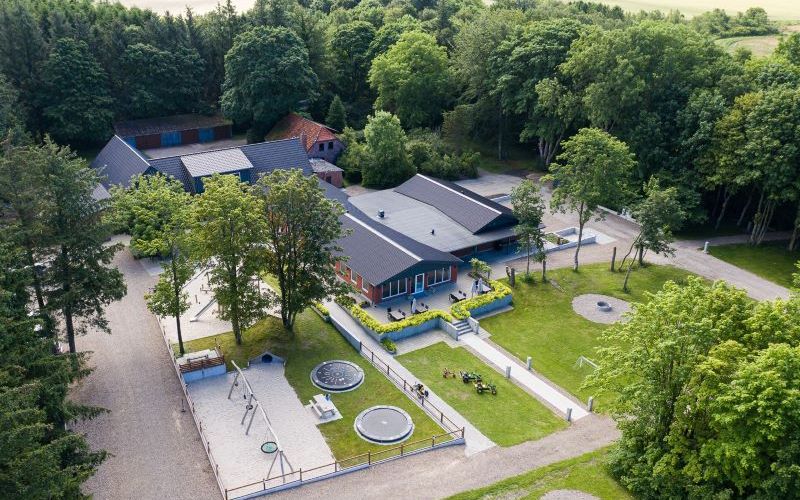 Dronefoto af Loasen Vesterhede - et overnatningssted ved Billund - med bygninger og den store legeplads
